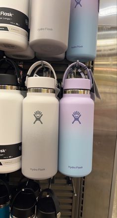 several hydro flasks are on display in a store, one is blue and the other is white