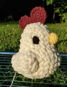 a crocheted chicken sitting on top of a metal rack