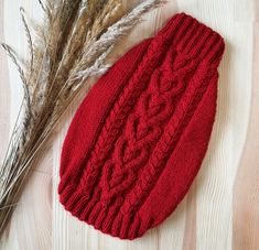 a red knitted hat sitting on top of a wooden floor next to dry grass