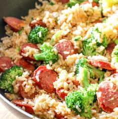 a skillet with rice, sausage and broccoli in it on a table