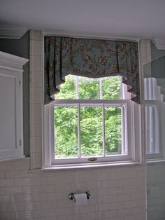 a bathroom with a sink, window and toilet paper roll on the counter in front of it