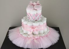 a pink and white diaper cake on top of a black table with tulle