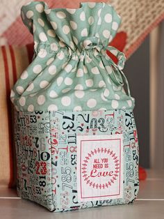 a polka dot gift bag sitting on top of a table next to a red and white pillow