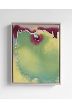 an abstract painting in green, yellow and purple on a white wall with a wooden frame