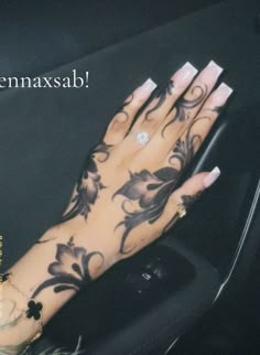 a woman's hand with black and white tattoos on it, sitting in a car