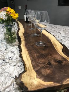 three wine glasses sitting on top of a wooden table next to vases with flowers