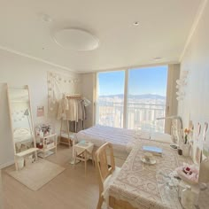 a bedroom with a bed, desk and large window overlooking the city in front of it