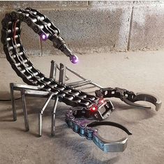 a metal sculpture made to look like a spider with chains and lights on it's legs