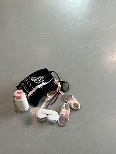 a pair of baby shoes sitting on top of a floor next to a bag and thread