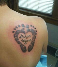 the back of a woman's shoulder with a heart shaped hand and foot print