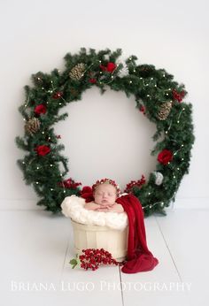 a baby in a bathtub surrounded by christmas wreaths