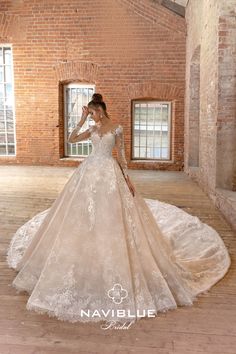 a woman in a wedding dress standing on a wooden floor next to a brick wall