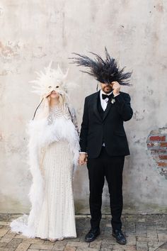 a man in a tuxedo standing next to a woman with feathers on her head