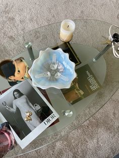 a glass table topped with pictures and candles on top of a carpeted floor next to a vase