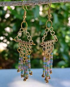 Handcrafted chandelier earrings created with gold chain pieces of varying lengths and a colorful array of seed beads. Multicolor Metal Dangle Chandelier Earrings, Multicolor Metal Chandelier Earrings, Gold Beaded Dangle Chandelier Earrings, Handmade Multicolor Metal Chandelier Earrings, Handmade Metal Multicolor Chandelier Earrings, Multicolor Metal Earrings With Dangling Beads, Gold Chandelier Earrings With Colorful Beads As Gift, Gold Beaded Metal Dangle Earrings, Multicolor Gold Beads Dangle Earrings