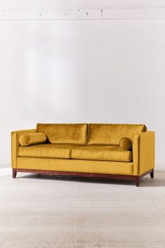 a yellow couch sitting on top of a hard wood floor next to a white wall