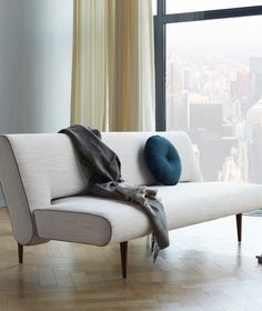 a white couch sitting in front of a window with a blanket on top of it