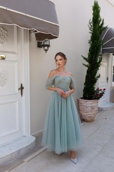 a woman standing in front of a white door wearing a dress with off the shoulder sleeves