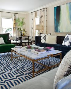 a living room filled with furniture and a painting on the wall above it's coffee table