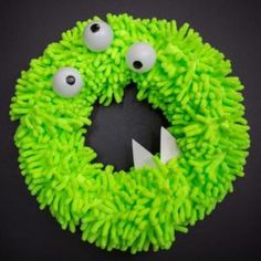 a green wreath with googly eyes and one eye on the front is made to look like a monster