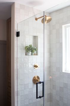 a bathroom with a glass shower door and white tile on the wall next to it