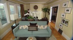 a living room with blue couches and white flowers in vases on the coffee table