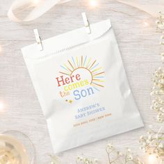 here comes the son personalized baby shower bag with ribbon and wine glass on white wooden background