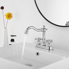 a white sink sitting under a mirror next to a vase with a yellow flower in it