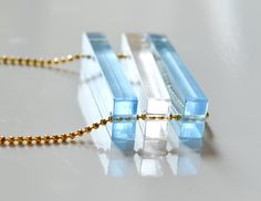 three pieces of glass sitting on top of a white table next to a beaded necklace