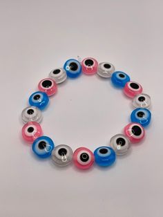 A cool multi-colored eye bead bracelet. Includes blue, pink, and clear beads. Pink Evil Eye Bracelet Jewelry, Adjustable Pink Evil Eye Bracelet, Adjustable Pink Beaded Evil Eye Bracelet, Pink Beaded Evil Eye Bracelet, Pink Beaded Evil Eye Bracelet With Round Beads, Handmade Pink Evil Eye Bracelet With Round Beads, Pink Evil Eye Round Beads Bracelets, Pink Bracelets With Evil Eye Round Beads, Pink Beaded Bracelets With Evil Eye