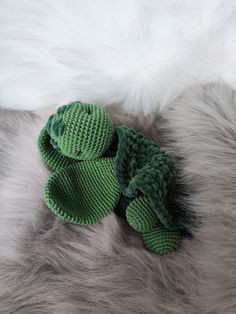 a green knitted frog toy laying on top of a fur rug