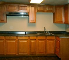 an empty kitchen with wooden cabinets and black counter tops