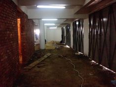 an empty hallway with exposed brick walls and steel bars on the wall, surrounded by debris