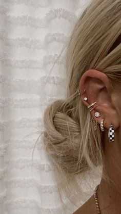 a woman with blonde hair is wearing ear cuff and earrings in the shape of checkered squares