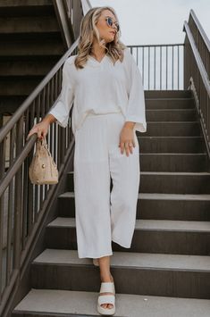 Full body view of female model wearing the Rebecca Ivory Linen Cropped Pants which features  Ivory Linen Fabric, Cropped Pant Legs, Ivory Lining, Two Side Pockets and Elastic Waistband Elegant Linen Pants For Loungewear, White Ankle-length Wide Leg Pants For Vacation, White Linen Ankle-length Bottoms, Elegant White Wide Leg Pants For Vacation, White Linen Wide Leg Vacation Pants, White Linen Wide Leg Pants For Vacation, Chic Linen Wide Leg Pants For Daywear, Chic Linen Pants For Daywear, Chic Neutral Pants For Vacation