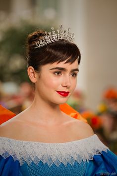 a woman with a tiara on her head wearing a blue dress and red lipstick