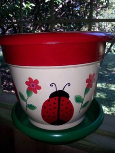 a red and white flower pot with a ladybug painted on it