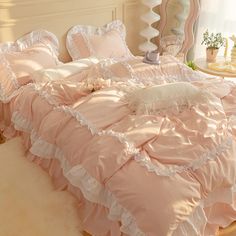 a pink bed with ruffled sheets and pillows