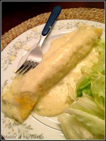 a white plate topped with meat and lettuce covered in gravy next to a fork