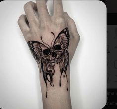 a hand with a butterfly tattoo on it and a skull in the middle of it