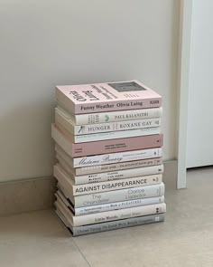 a stack of books sitting on top of a floor next to a white wall and door