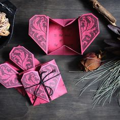 an origami heart shaped box sitting on top of a table next to dried leaves