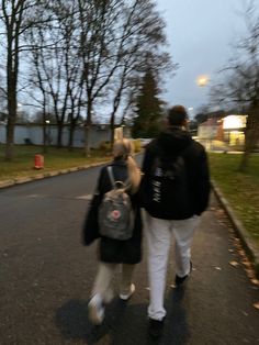 two people walking down the street with a teddy bear on their back and one person carrying a backpack