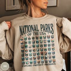 "Celebrate all 63 US National Parks with our custom \"National Parks of the USA\" sweatshirt from Triangle Threads. This crewneck features unique badge designs for ALL 63 US NATIONAL PARKS! The Gildan 18000 50/50 blend fabric has that comfy, lived-in feel, that's like a hug every time you put it on! Now you can take a bit of all the parks with you wherever you wander! Grab one while you can, and hit the trail! * Product Highlights * Ideal for any situation, this Gildan 18000 heavy blend crewneck National Park Gifts, National Park Shirt, Usa Sweatshirt, Cowboy Christmas, Us National Parks, Granola Girl, Badge Design, A Hug, 50 50