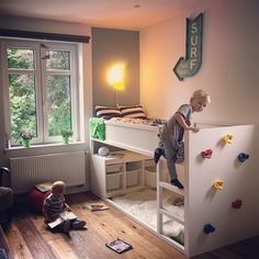 a young boy climbing up the side of a bunk bed in a bedroom next to a window