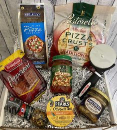 an open gift box filled with pizza, pasta and other food items on a wooden table