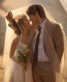 a bride and groom standing under an umbrella