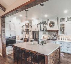 a kitchen with white cabinets and an island in the middle, surrounded by wooden flooring