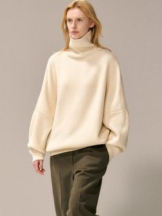 This luxurious oversized turtleneck sweater features a 15% wool blend composition and sophisticated drop-shoulder design that extends below the hip, offering versatile styling options from casual to dressy. The relaxed silhouette and premium fabric blend of wool, nylon, and acrylic create the perfect balance of comfort and elegance for year-round wear. Available in beige, brown, and black, this versatile piece can be worn alone during transitional seasons or layered under outerwear for added war Oversized Beige Sweater With Ribbed Collar, Beige Wool Turtleneck For Fall, Classic Oversized Turtleneck Sweater, Beige Turtleneck Sweater For Work, Oversized Merino Wool Sweater With Ribbed Collar, Beige Funnel Neck Turtleneck For Work, Cream Turtleneck With Ribbed Collar For Fall, Oversized Cream Merino Wool Sweater, Wool Turtleneck For Workwear