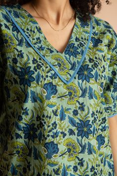 a woman wearing a blue and green floral top